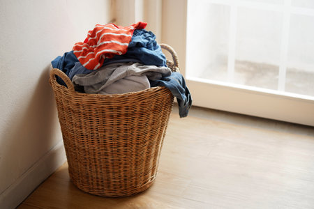 Wooden wicker basket that holds lots of used clothes and prepares them for washing.の写真素材