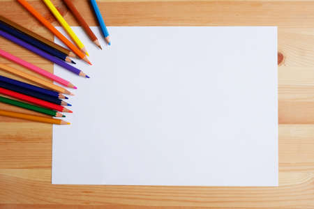 Color pencils and white paper with empty space to put messages on wooden table, Concept of learning for students or children. top viewの写真素材