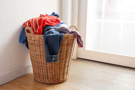 Wooden wicker basket that holds lots of used clothes and prepares them for washing.の写真素材