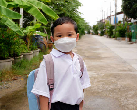 Portrait of Asian boy student in school uniform wearing a white shirt with backpack wearing mask go to school, back to school concept during the covid 19 epidemicの写真素材