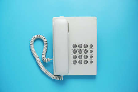 White land phone with grey buttons isolated on blue or pastel backgroundの写真素材