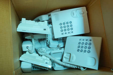 Many piles of broken or unused landline telephone are thrown in cardboard boxes, Communication technology that has changed with the timesの写真素材