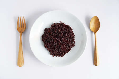Riceberry cooked in white plate with wooden cutlery on white background, top view, Organic healthy clean food is rich in antioxidants and high in fiberの写真素材