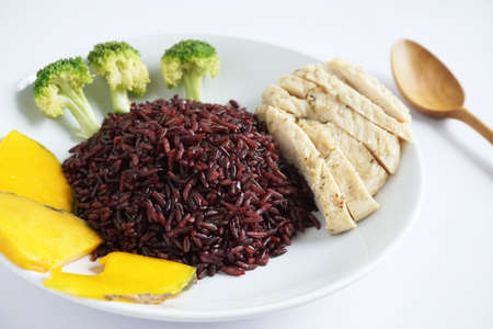 Close-up of riceberry cooked and chicken breast with Boiled broccoli and pumpkin on a white plate on a white background Healthy, clean organic food, rich in antioxidants and high in fiberの写真素材
