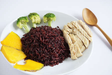 Close-up of riceberry cooked and chicken breast with Boiled broccoli and pumpkin on a white plate on a white background Healthy, clean organic food, rich in antioxidants and high in fiberの写真素材