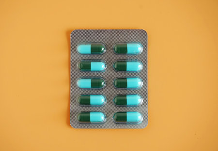 Blue-green capsule pill panel on orange background. Amoxicillin is a penicillin antibiotic. It is used to treat infections caused by bacteriaの写真素材