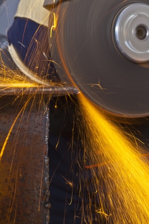 A man working with grinder, close up on tool, sparks fly, real situation pictureの写真素材