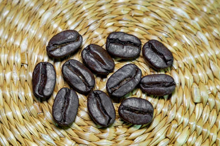 black coffee grains scattered on a braided authentic background, photographed from above close-up