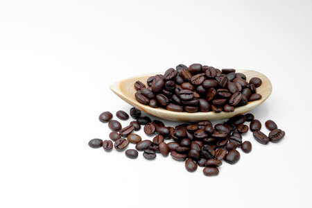black coffee grains in wooden authentic dishes and, scattered on a white backgroundの写真素材