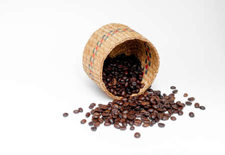 black coffee grains in a braided authentic basket and, scattered on a white backgroundの写真素材