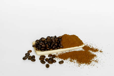 black coffee grains and ground coffee poured into wooden dishes, filmed on a white backgroundの写真素材