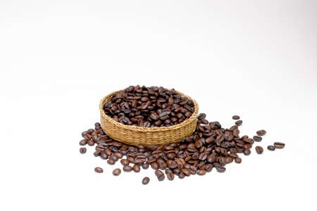 black coffee grains in a braided authentic basket and, scattered on a white backgroundの写真素材