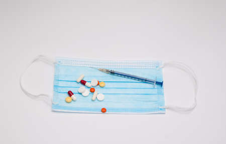 Medical mask, pills and syringe on a white background. Coronavirus concept.の写真素材