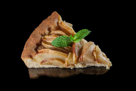 triangular apple cake on a black background with reflection decorated with mint leafの写真素材