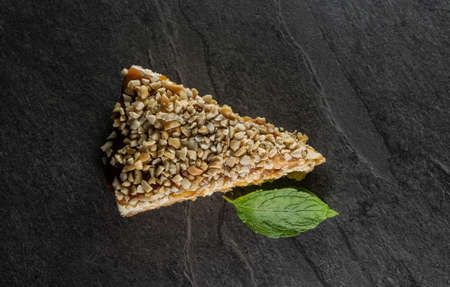 triangular nut cake on a gray stone background decorated with mint leafの写真素材