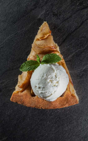 triangular apple cakes on a gray stone background decorated with a ball of ice cream and mint leafの写真素材