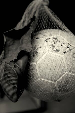 A random still life of a toddlers shoe with a piece of fabric and a volleyball inside a fishing net.の写真素材