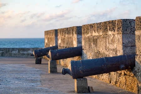 Cannons lined up in the sunset with the Caribbean sea in the background in Cartagena, Colombia.の写真素材