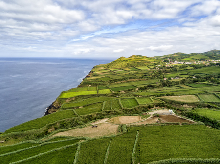 Aerial view of fields and Atlantic Ocean with the village of Ginetes in the background on Sao Miguel Island in Portugal.の写真素材