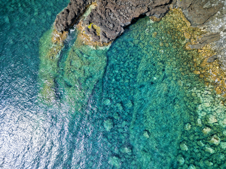 Aerial shot of a lava formation and the beautiful blue waters of the atlantic near Canada de Africa on Sao Jorge in the Azores.の写真素材