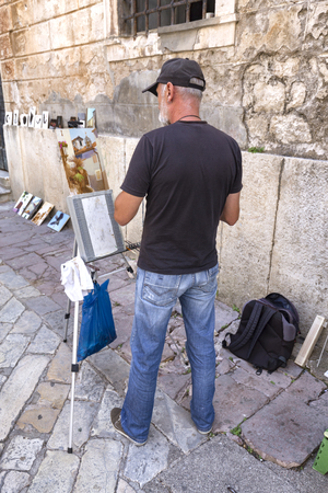 KOTOR, MONTENEGRO - AUGUST 12: An unidentified painter near the Saint Michael Church in Kotor, Montenegro on August 12, 2016.のeditorial素材