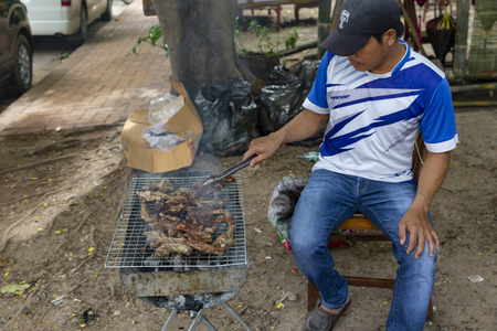 LUANG PRABANG, LAOS - OCTOBER 4: Unidentified man grills meat on the side of the road on October 4, 2017 in Luang Prabang, Laos.のeditorial素材