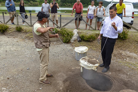 FURNAS, PORTUGAL - AUGUST 4: An unidentified chef and his helper dig out Cozido, an Azores meal cooked in the ground near thermal vents at Fumarolas da Lagoa das Furnas in Furnas, Portugal on August 4, 2017.のeditorial素材