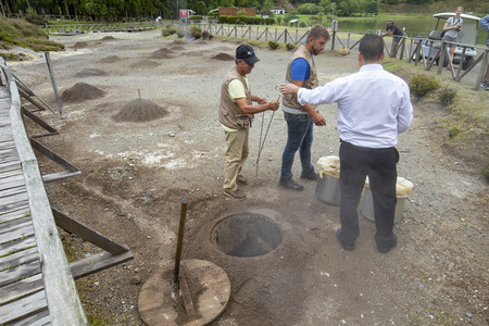 FURNAS, PORTUGAL - AUGUST 4: Unidentified people people watch as a chef takes out Cozido, an Azores meal cooked in the ground near thermal vents at Fumarolas da Lagoa das Furnas in Furnas, Portugal on August 4, 2017.のeditorial素材