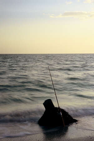 Fishing pole on beach at sunsetの写真素材