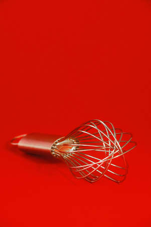 Wire whisk on red backgroundの写真素材