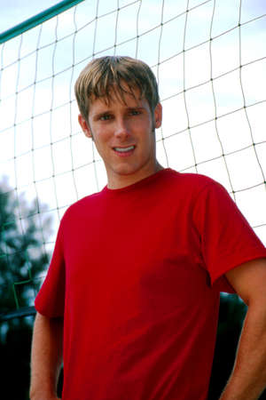  Young man standing in front of volleyball netの写真素材