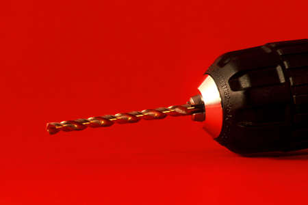 Closeup of a drill bit on a drill on a red backgroundの写真素材