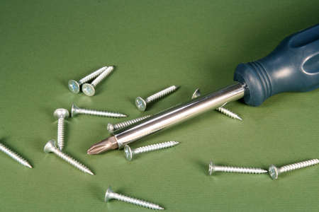 Phillips screwdriver and screws on a green background