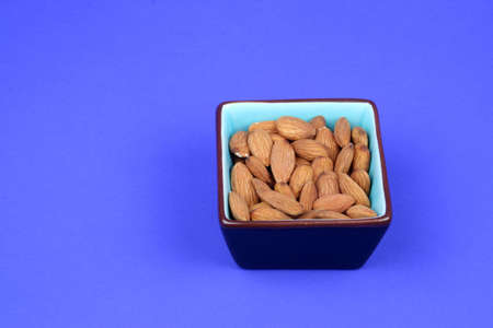 Almonds in a square dish on a blue backgroundの写真素材