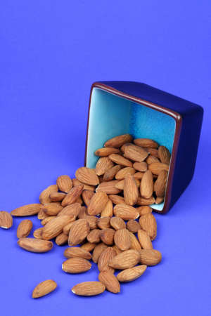 Almonds spilling out of a blue dishの写真素材