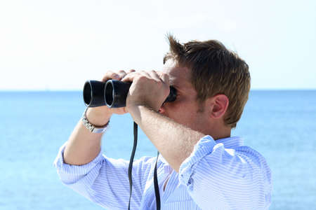 Man on beach looking through binoculars