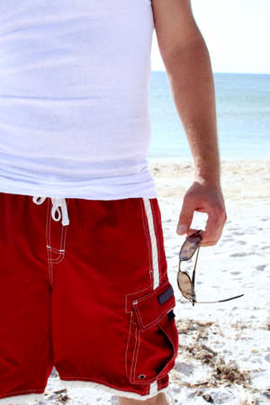 Sunglasses in man's hand at beachの写真素材