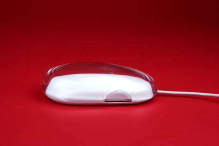 White computer mouse on a red backgroundの写真素材