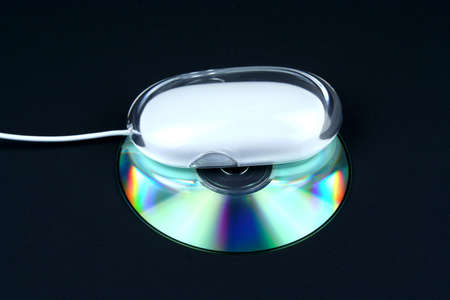 Cd under a computer mouse on a black backgroundの写真素材
