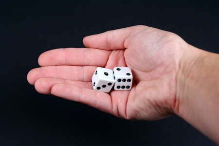 Two dice in hand on a black backgroundの写真素材