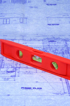Red level laying over a blueprint of houseの写真素材