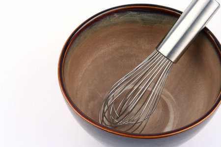 Wire whisk in an empty brown bowlの写真素材