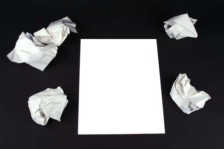 Piece of white paper on a black background with wads of crumpled paper around it