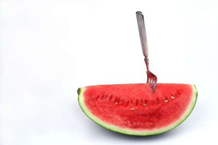 Close up of a fork in a piece of watermelon on a white backgroundの写真素材