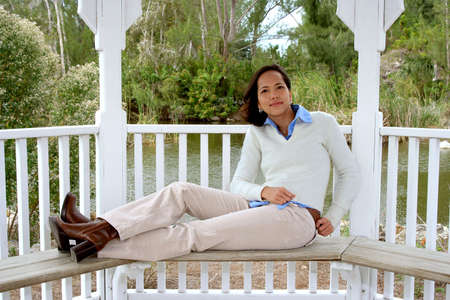 Photo of an attractive young woman lounging  on a benchの写真素材