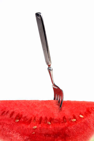 piece of watermelon on a white background with a fork in itの写真素材