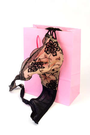 Black lacy bra falling out of a pink shopping bagの写真素材