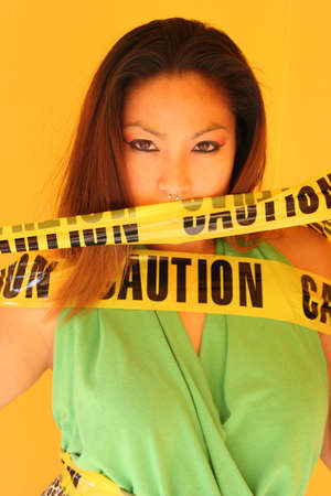 Young woman posing with yellow caution tapeの写真素材