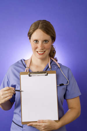 Female doctor in blue scrubs with a blank clipboardの写真素材