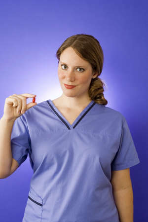 Female doctor in blue scrubs holding pillの写真素材